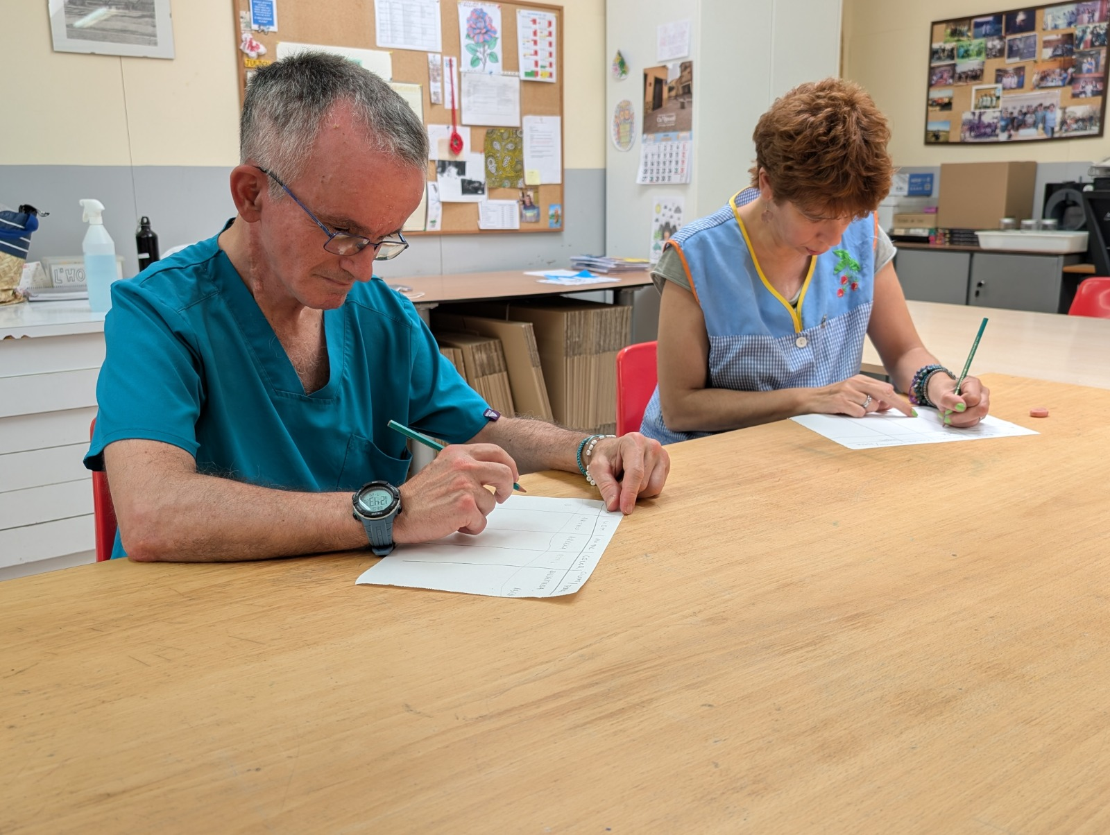 Adults escrivint a taula en una activitat del Centre Ocupacional