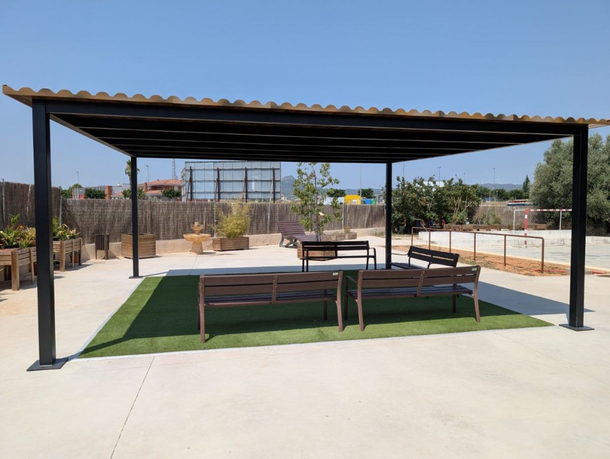 Espai exterior amb pèrgola i bancs, entorn tranquil i accessible