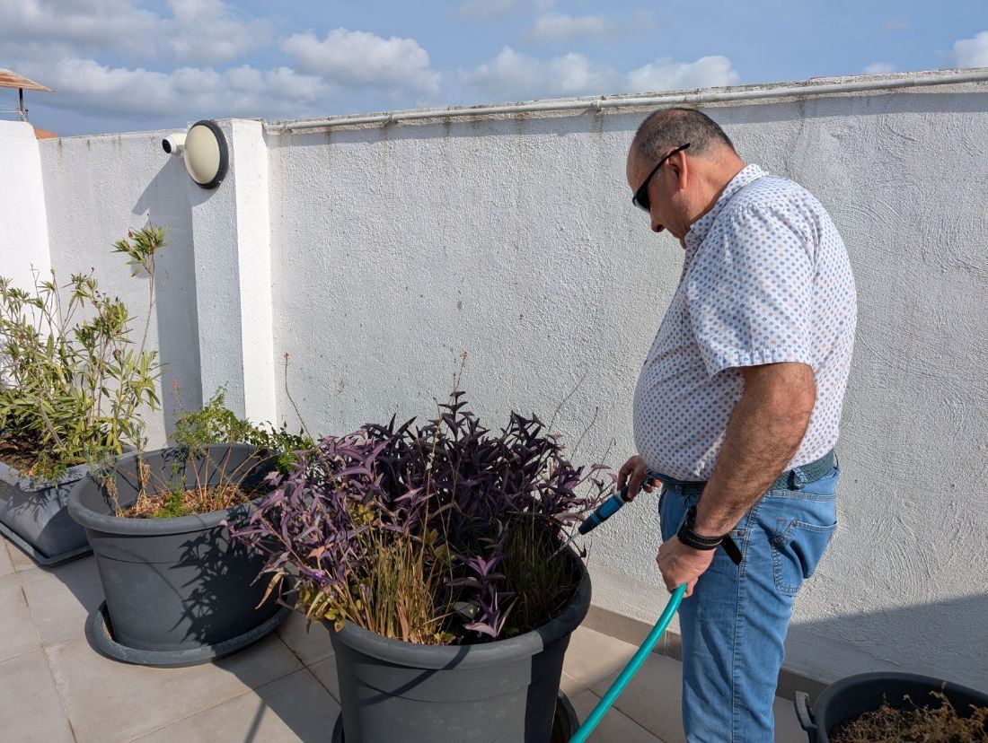 Persona gran regant plantes en una activitat de benestar físic i mobilitat
