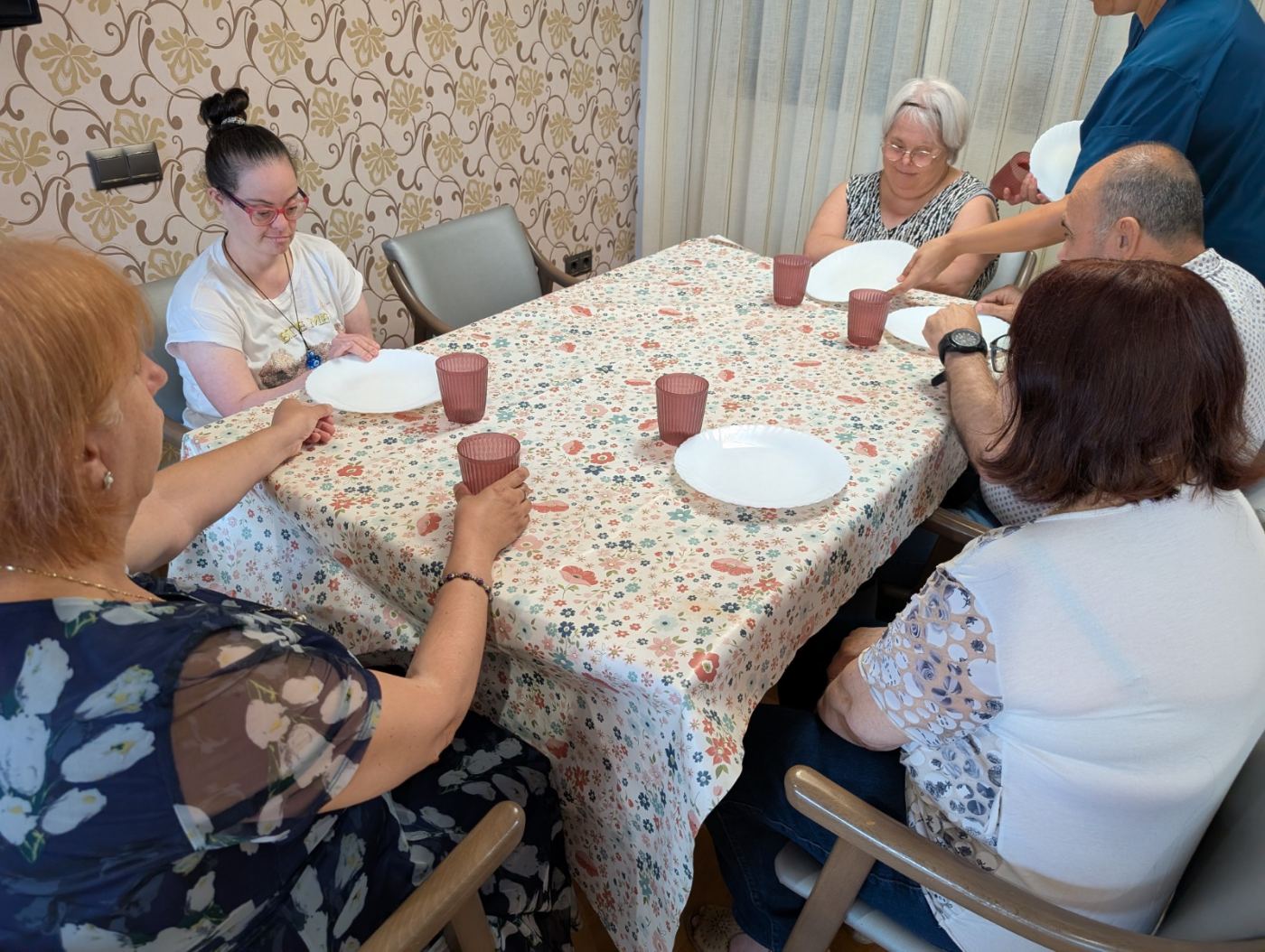 Grup de persones dinant juntes a la taula de la Llar